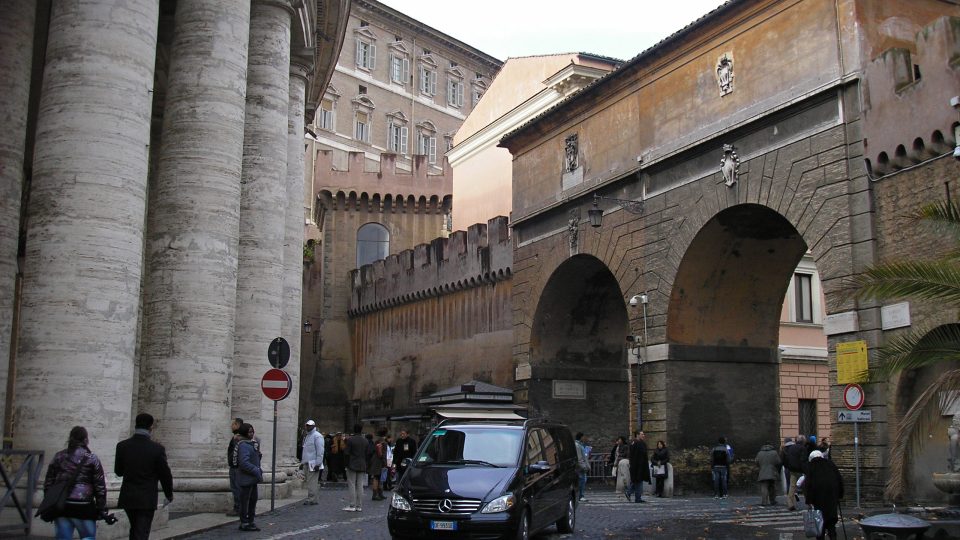 Andělská brána v ochranných hradbách kolem Vatikánu. Vlevo jsou vidět sloupy Michelangelovy kolonády
